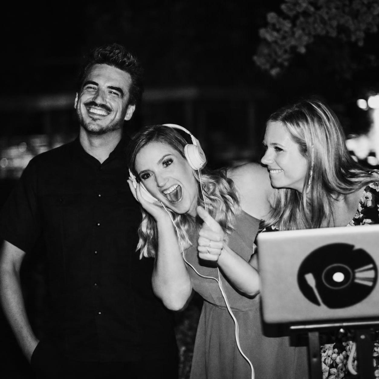 The Modern Wedding DJs team smiling behind the DJ booth at a reception