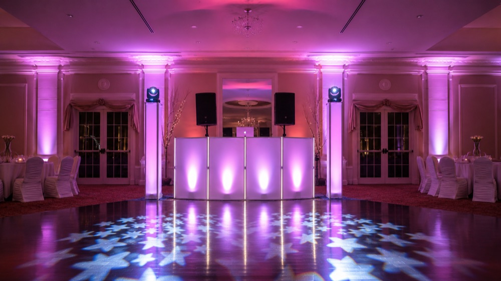 Club-style dance lighting with a DJ booth and patterned dance floor