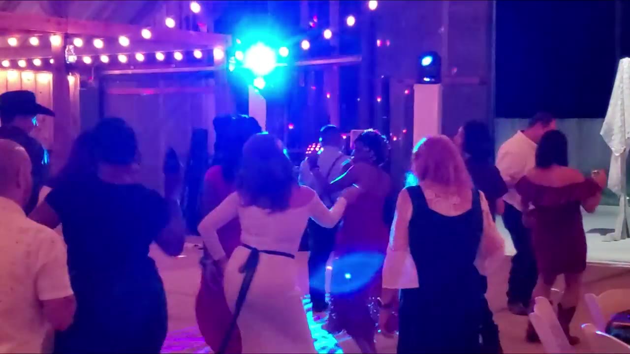 Guests dancing at a Northern California barn wedding reception under blue uplighting