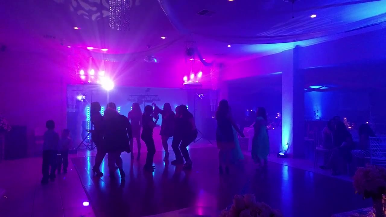 Guests dancing in an elegant ballroom glowing with purple and pink uplighting