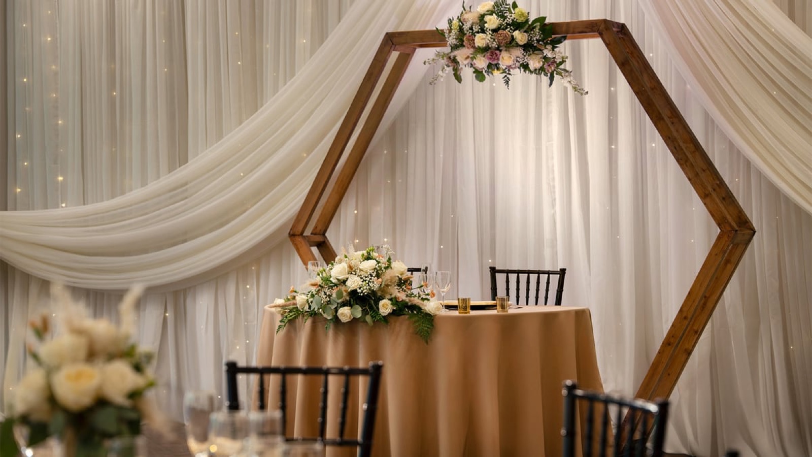 Elegant sweetheart table with hexagonal wood arch and floral arrangements at San Ramon Golf Club wedding venue in San Ramon, California